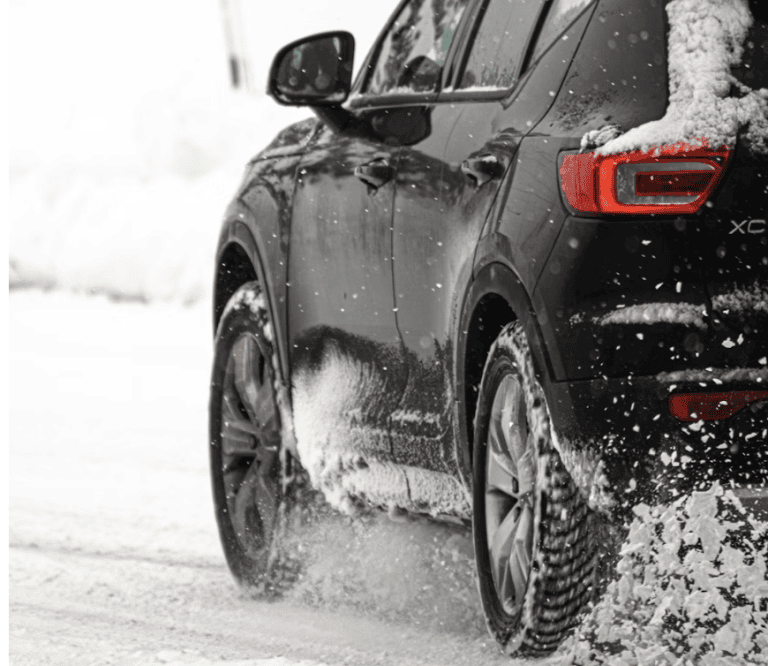 tight shot of tires on black Volvo driving in snow
